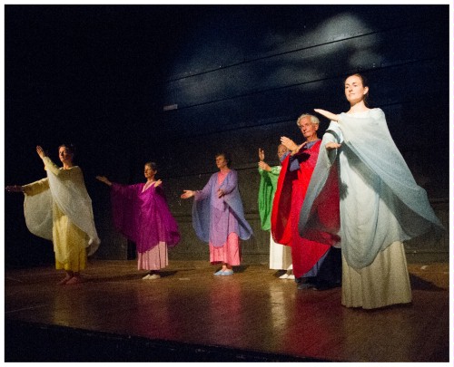 (Image: Dancers in Rows with
  Clouds Projected on the Wall Behind)