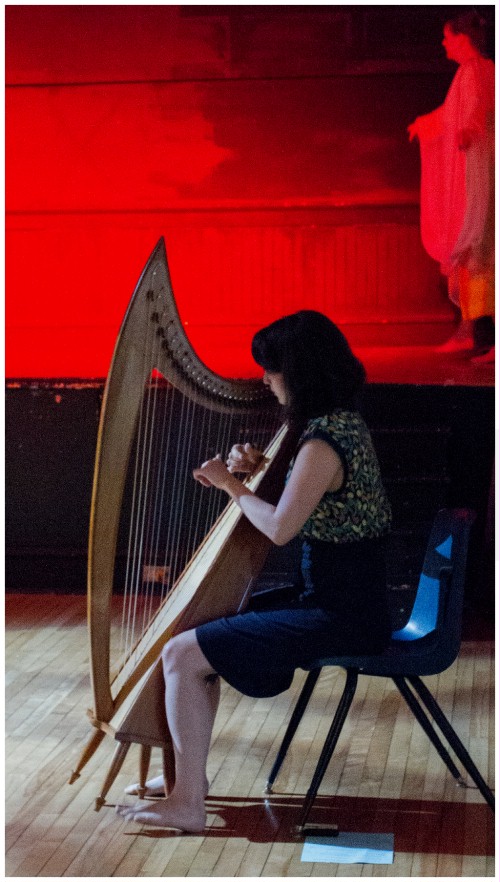 (Image: Harpist Ellen Performs on
  the Hall's Main Floor as a Dancer Enters the Stage)